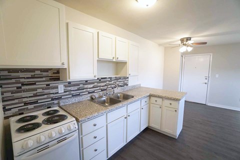 A kitchen with white cabinets and a granite countertop.