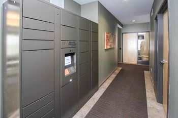 A long hallway with a row of lockers on the left and a door on the right.