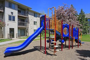 A playground with a blue slide and orange and blue play structure.