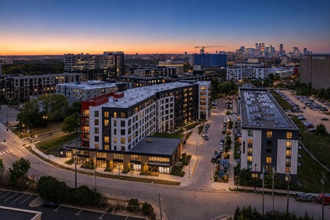 A cityscape at dusk with buildings and a parking lot.