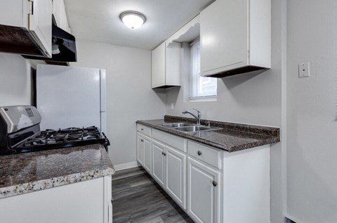 a kitchen with white cabinets and granite counter tops and a stove and refrigerator