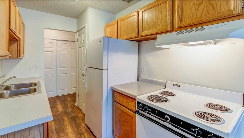 A kitchen with a white stove top oven and a white refrigerator.