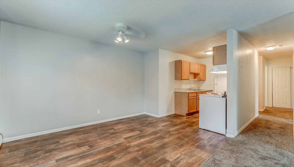 A kitchen area with a white refrigerator and wooden flooring.