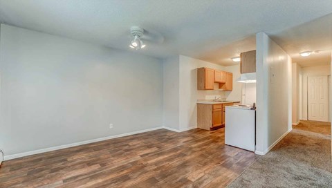 A kitchen area with a white refrigerator and wooden flooring.
