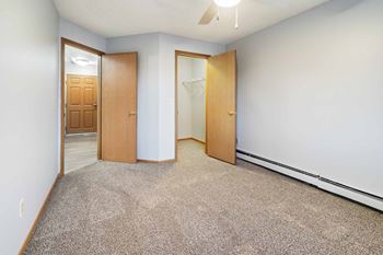 A room with a carpeted floor and two wooden doors.