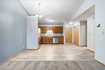 A kitchen area with wooden cabinets and a grey rug on the floor.