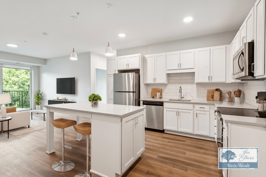 a large white kitchen with an island and stainless steel appliances