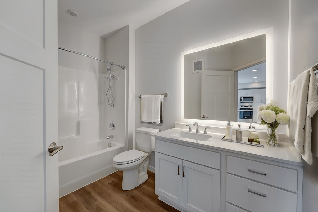 a white bathroom with a large mirror and a white toilet and sink