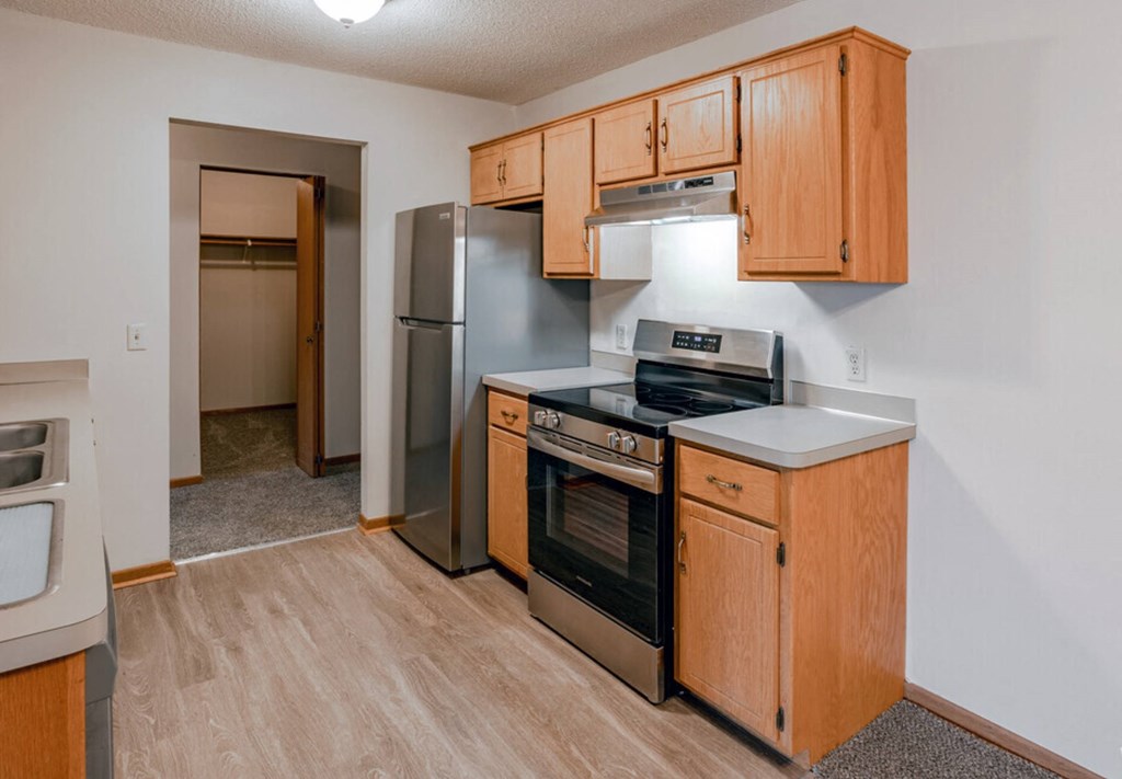 an empty kitchen with wooden cabinets and stainless steel appliances