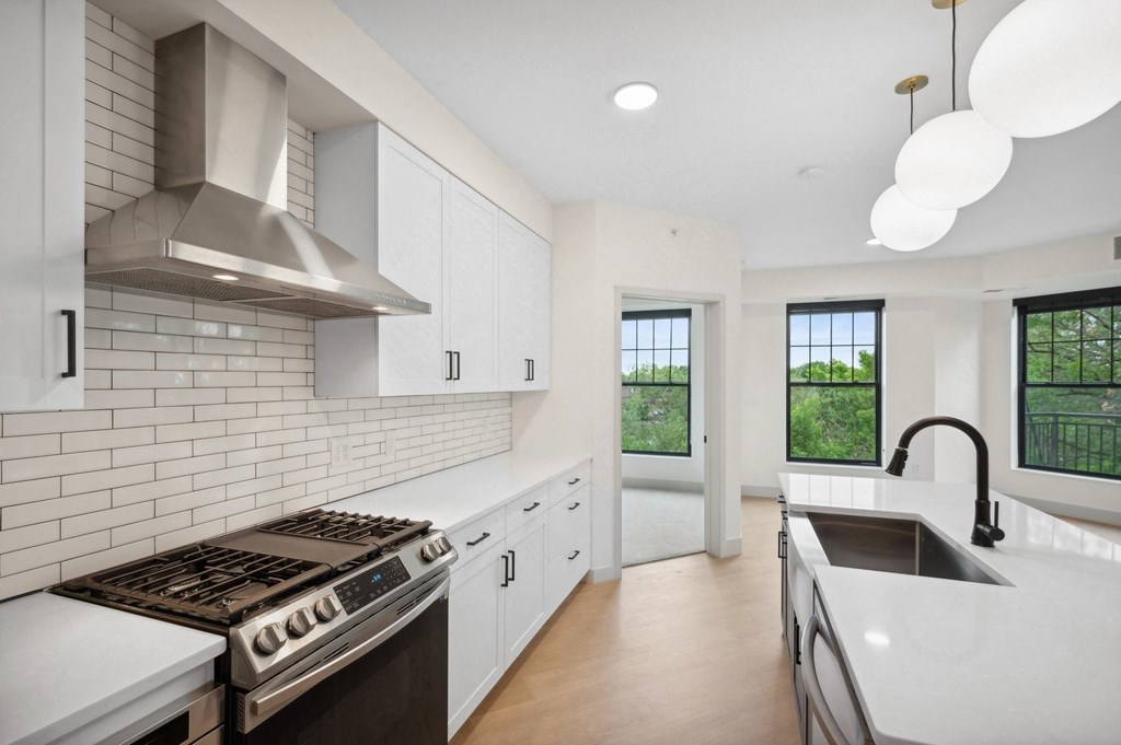 a kitchen with white cabinets and a sink and a stove