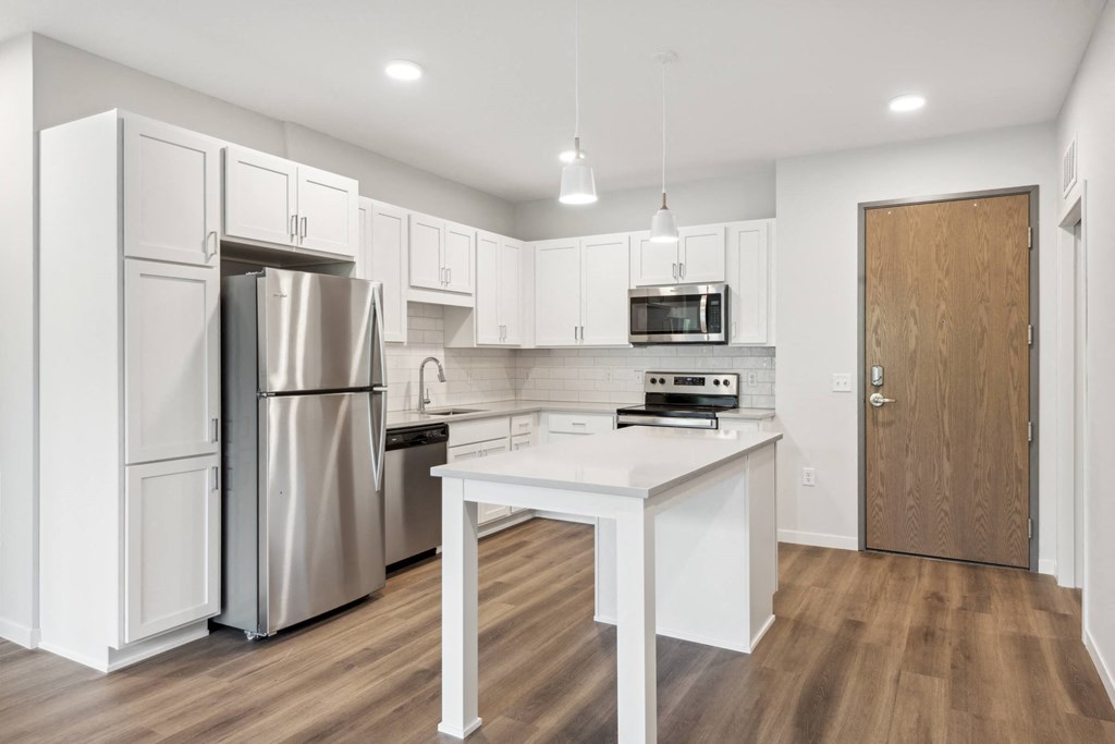 a white kitchen with stainless steel appliances and a white island