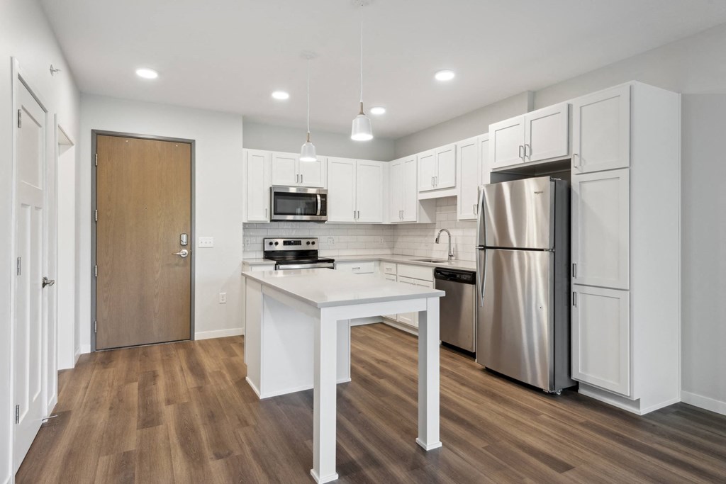 a white kitchen with stainless steel appliances and a white island