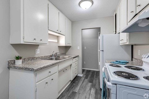 A kitchen with white cabinets and a granite countertop.