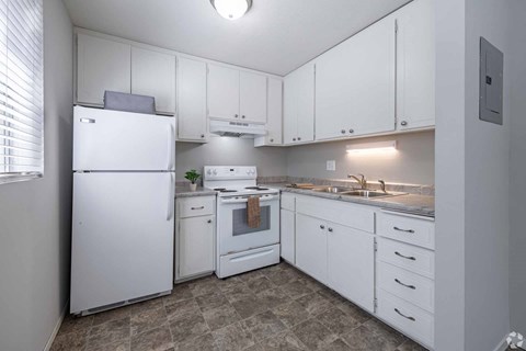 A white kitchen with a refrigerator, oven, and sink.