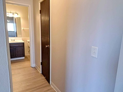 a bedroom with a door to a bathroom with a sink and a mirror