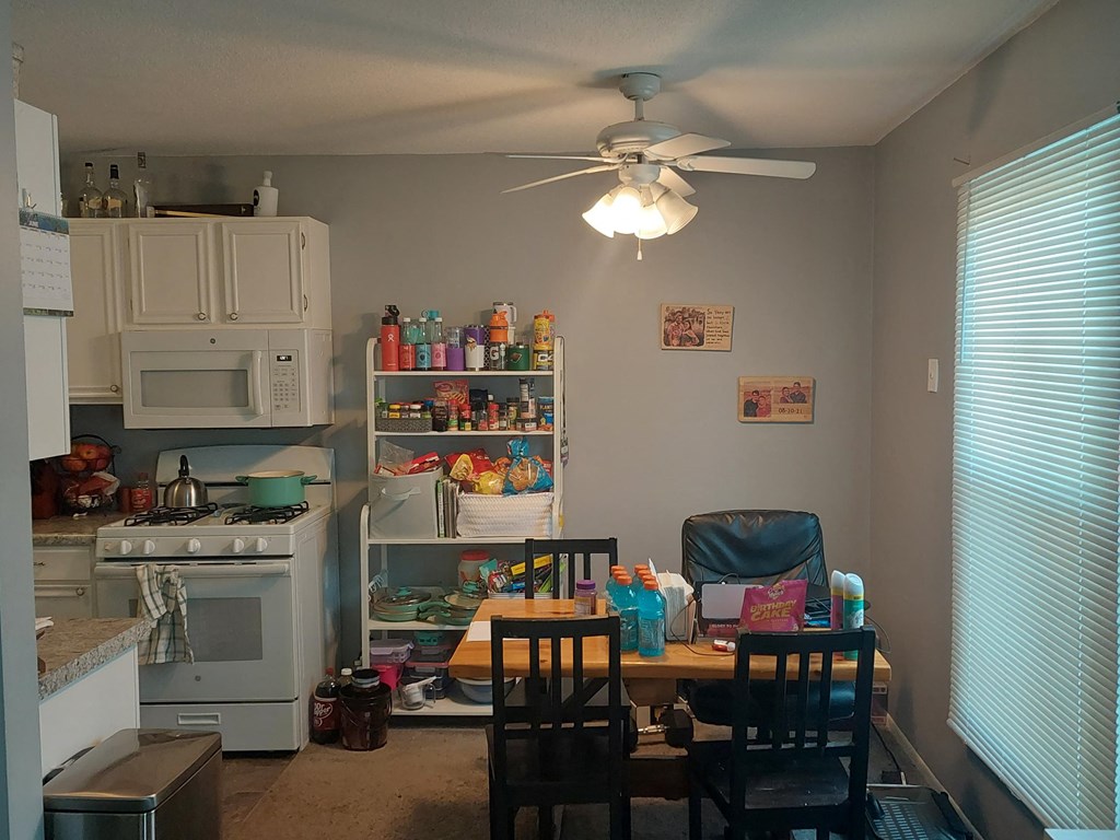 a kitchen with a table and chairs and a ceiling fan