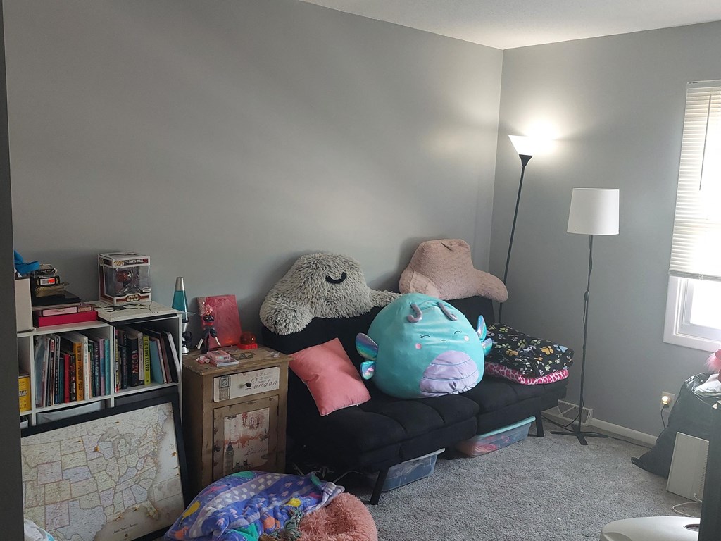 a living room with gray walls and a black couch with a bunch of pillows on it