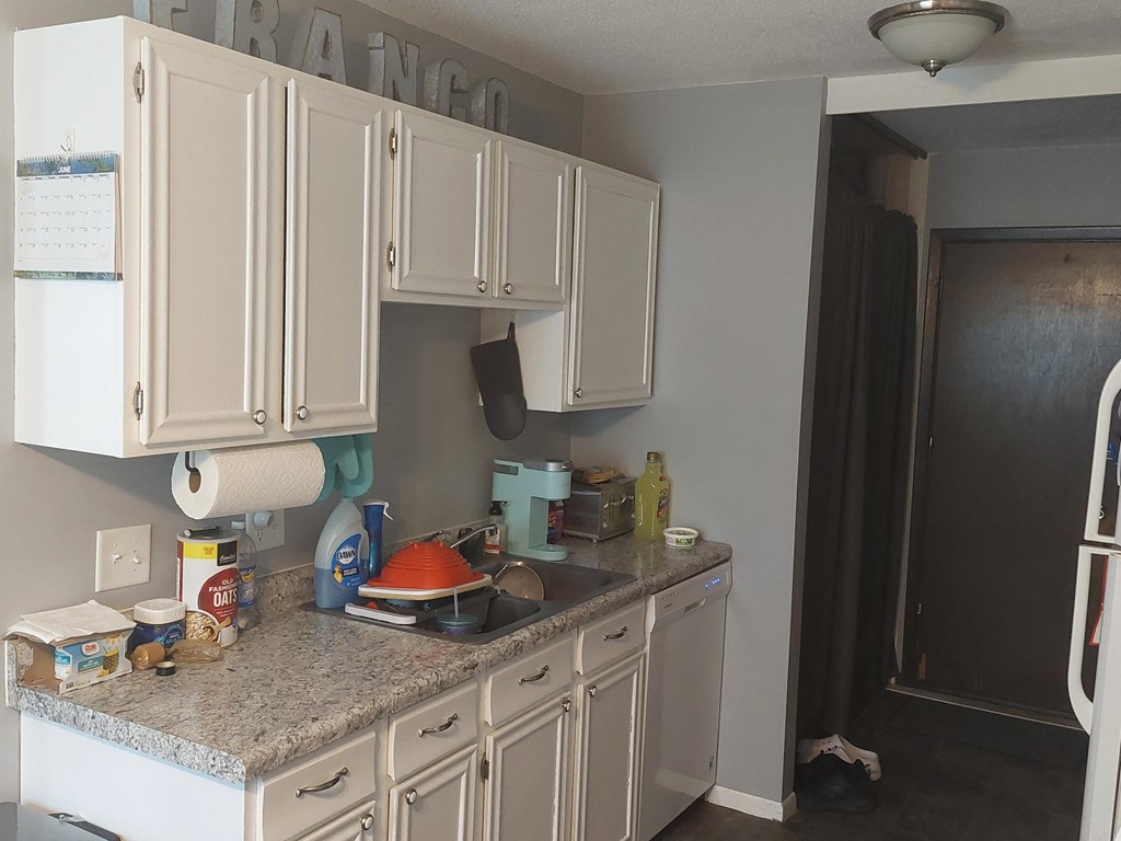 a kitchen with white cabinets and granite countertops