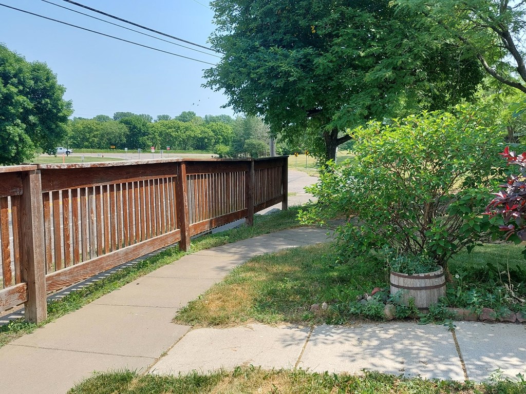 a sidewalk with a wooden fence on one side and a grassy area on the other