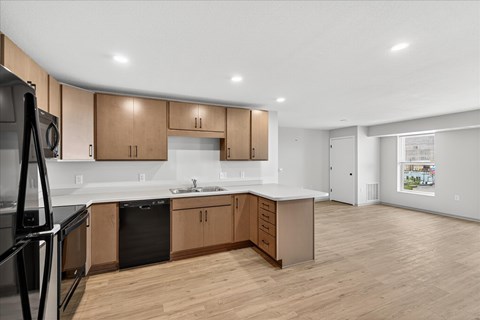 A kitchen with wooden cabinets and a black fridge.