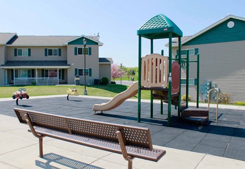 A playground with a wooden slide and a green roofed structure.