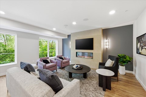 A modern living room with a grey couch and a fireplace.