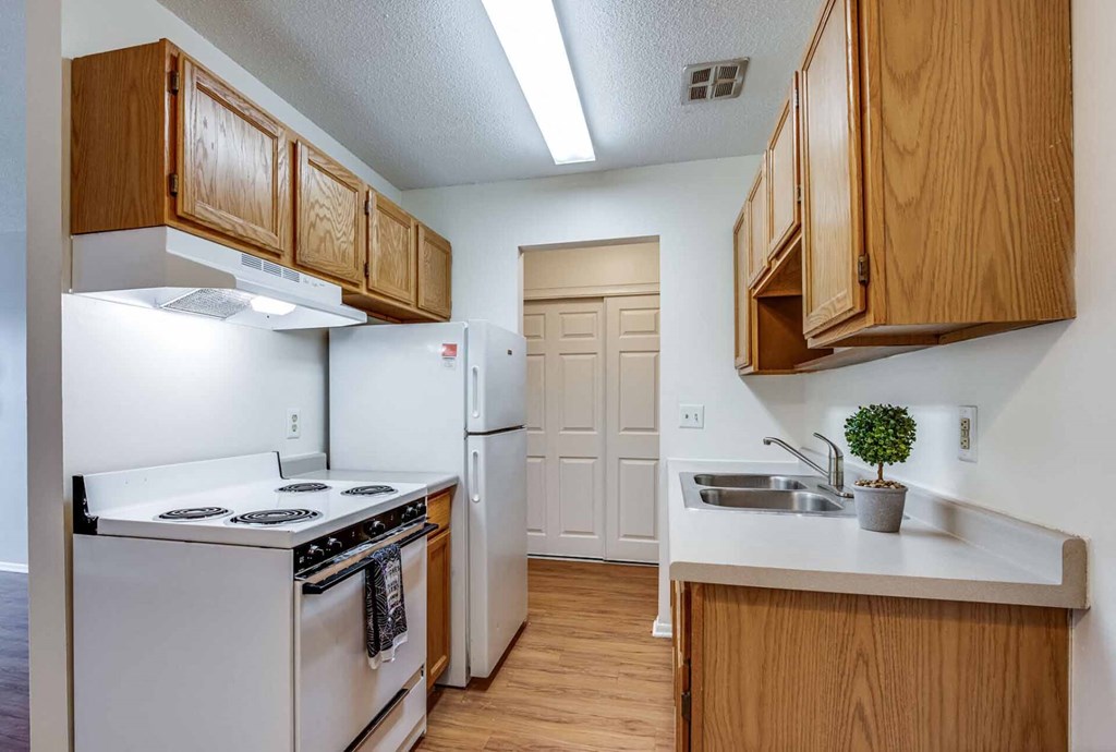 A kitchen with white appliances and wooden cabinets.