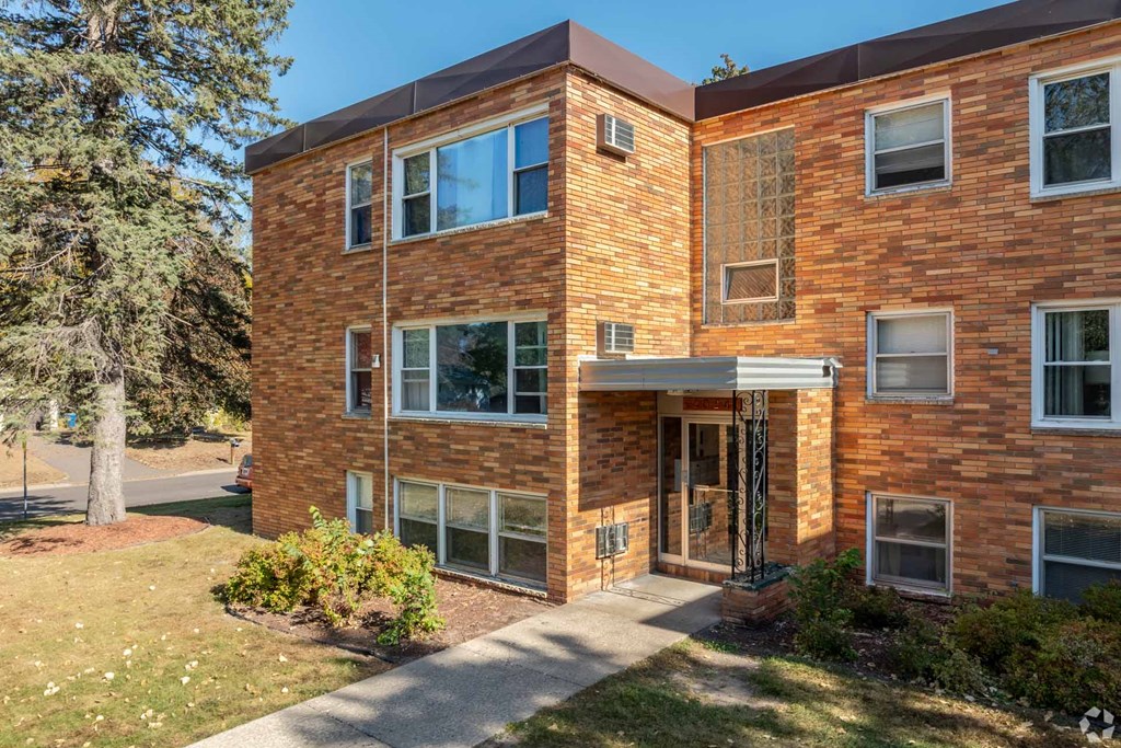 A red brick building with a tree in front of it.