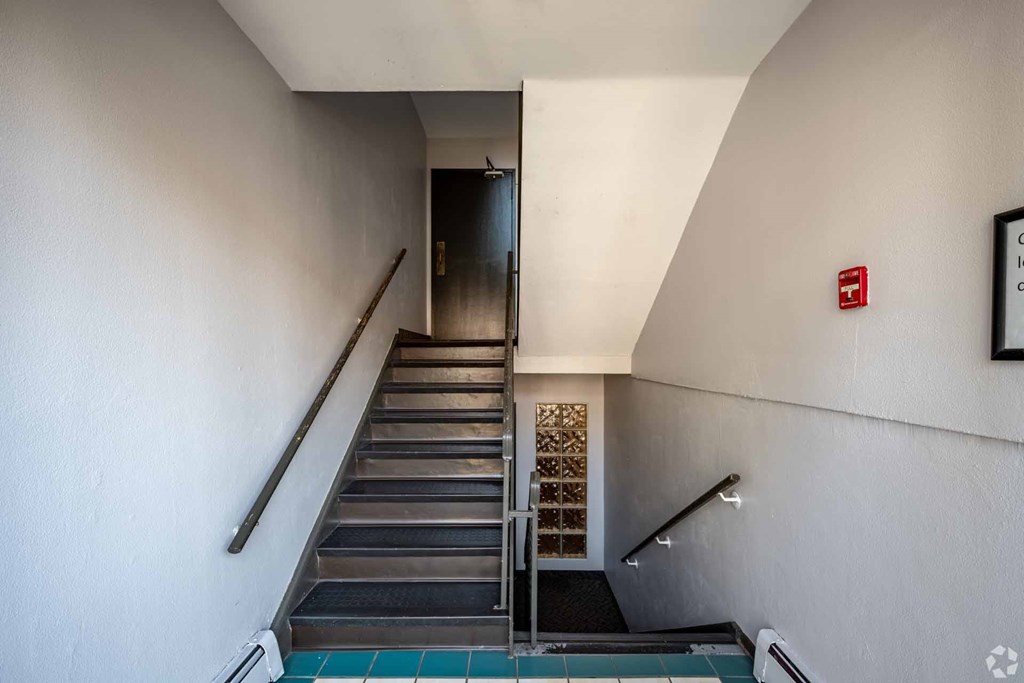 A staircase with a metal railing and steps leading to a door.