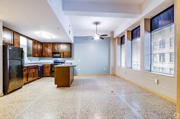 A kitchen with a black fridge and wooden cabinets.