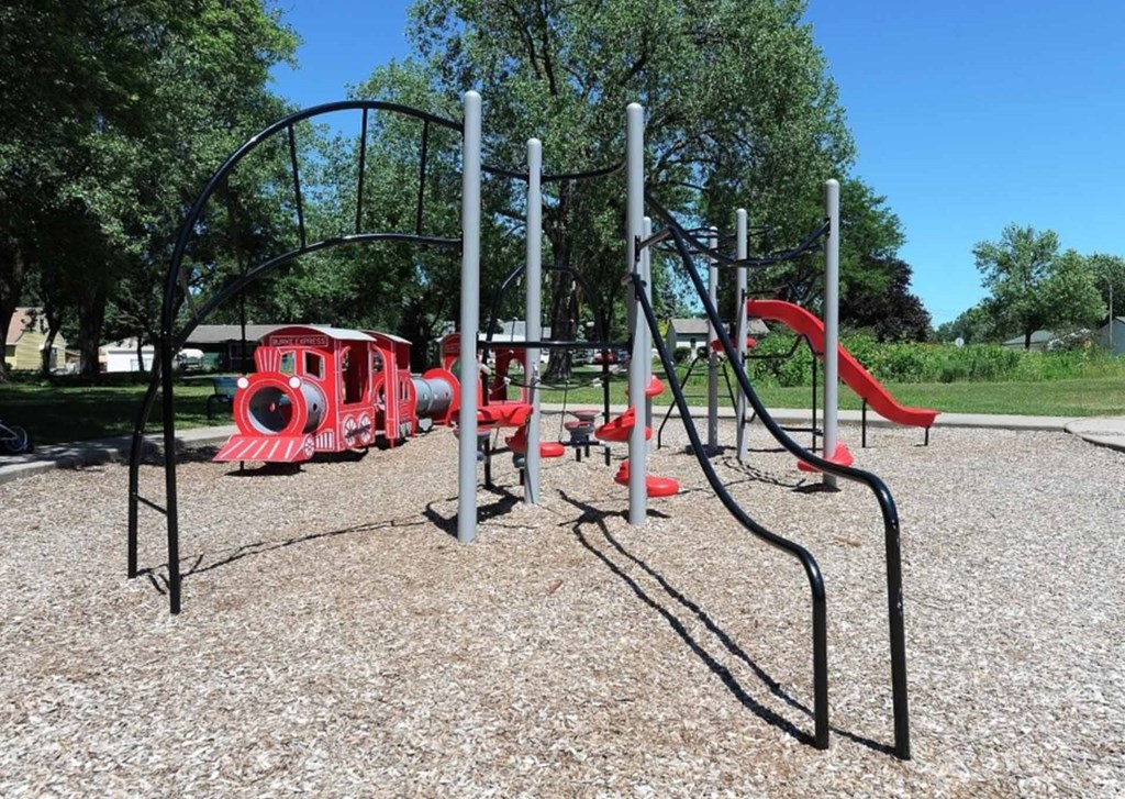 A playground with a red slide and a black metal structure.