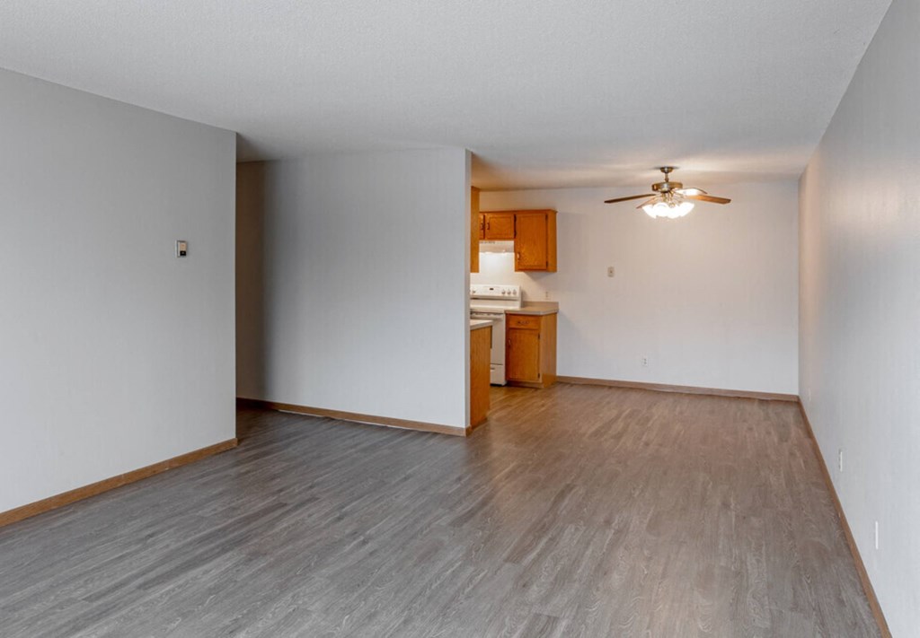 the living room and kitchen of an empty house with wood flooring
