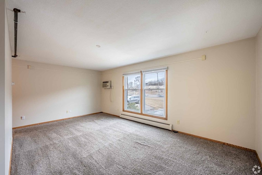 A room with a carpeted floor and a window.