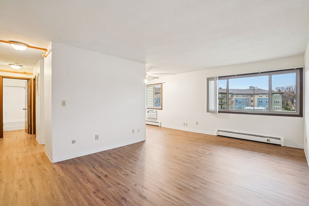 A room with wooden floors and a window overlooking a building.