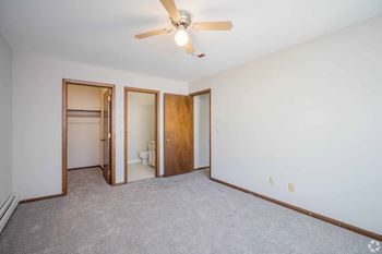 A room with a ceiling fan and three doors.