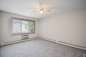 A room with a ceiling fan and a window with blinds.