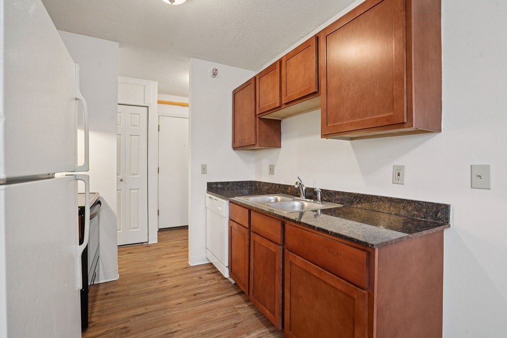 A kitchen with brown cabinets and a white fridge.