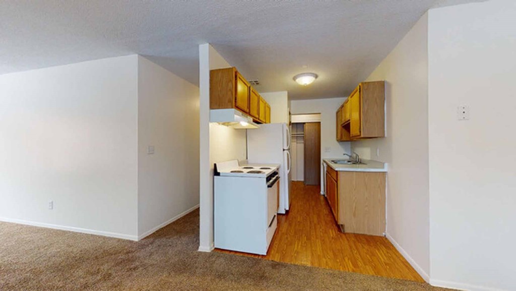 A kitchen with white appliances and wooden cabinets.