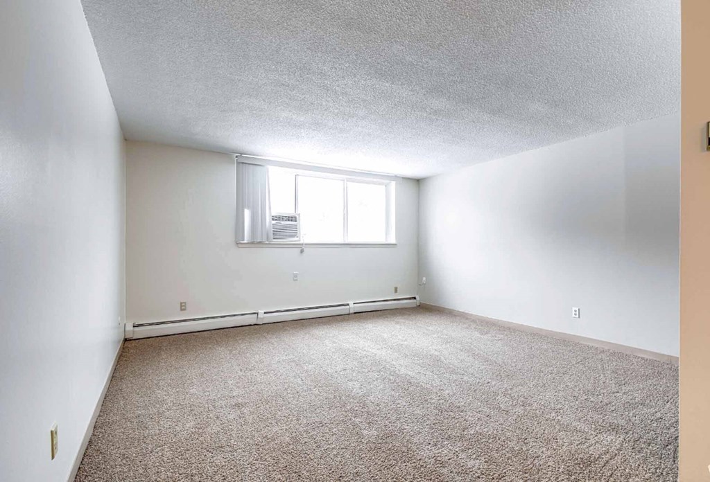 A room with a window and carpeted floor.