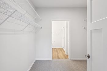 a bedroom with white walls and a door to a closet