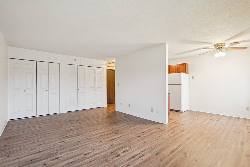 A room with a ceiling fan and wooden floors.