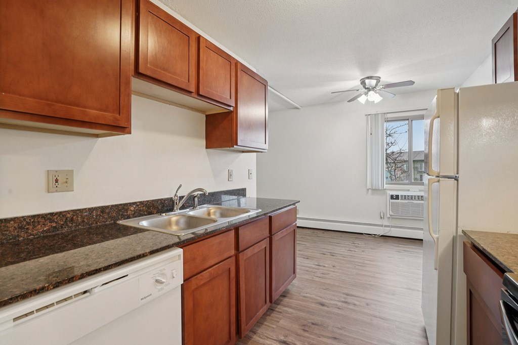 A kitchen with brown cabinets and a white dishwasher.