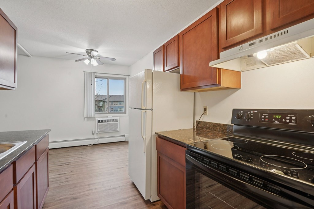 A kitchen with a black stove top oven and a white refrigerator.