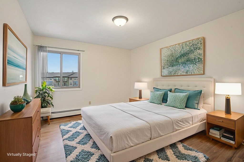 A bedroom with a large bed, a nightstand, and a painting on the wall.