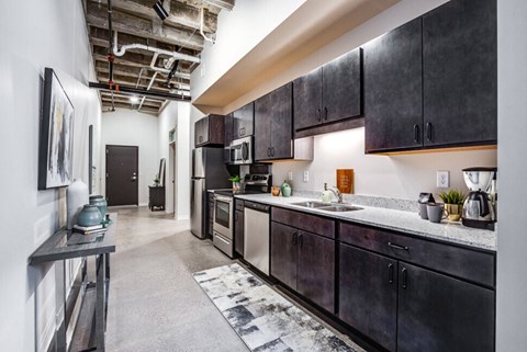 a kitchen with dark cabinets and a sink and a refrigerator