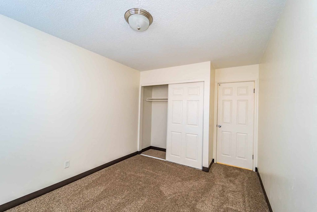 A room with a carpeted floor and two doors.