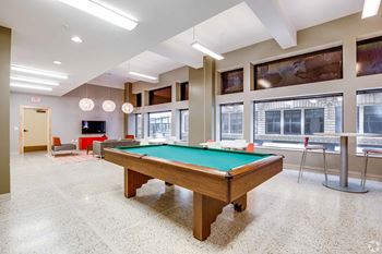 A pool table in a room with a chair and a TV.