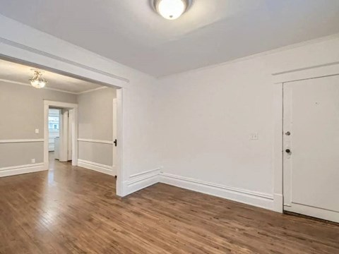 an empty living room with white walls and wood floors
