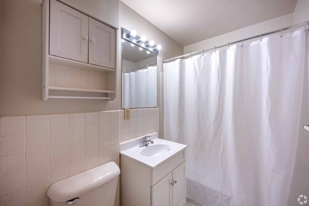 A white bathroom with a sink, toilet, and shower curtain.