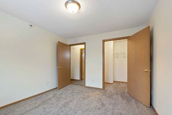 A room with a carpeted floor and three doors.